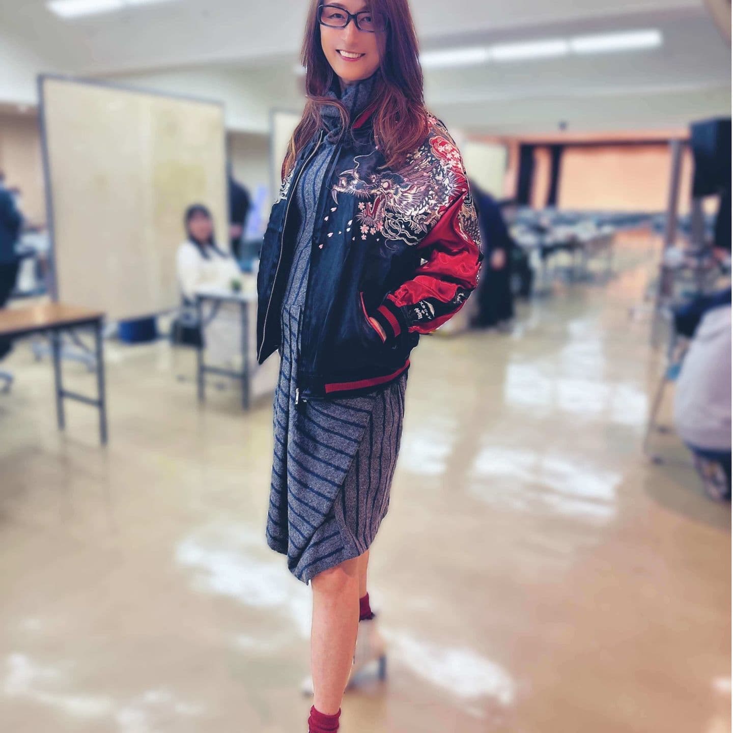 華やかなスカジャンを羽織り微笑む薬真寺紀子さん。着物ドレスと融合したスタイルで、文化とファッションの架け橋となる観光大使。